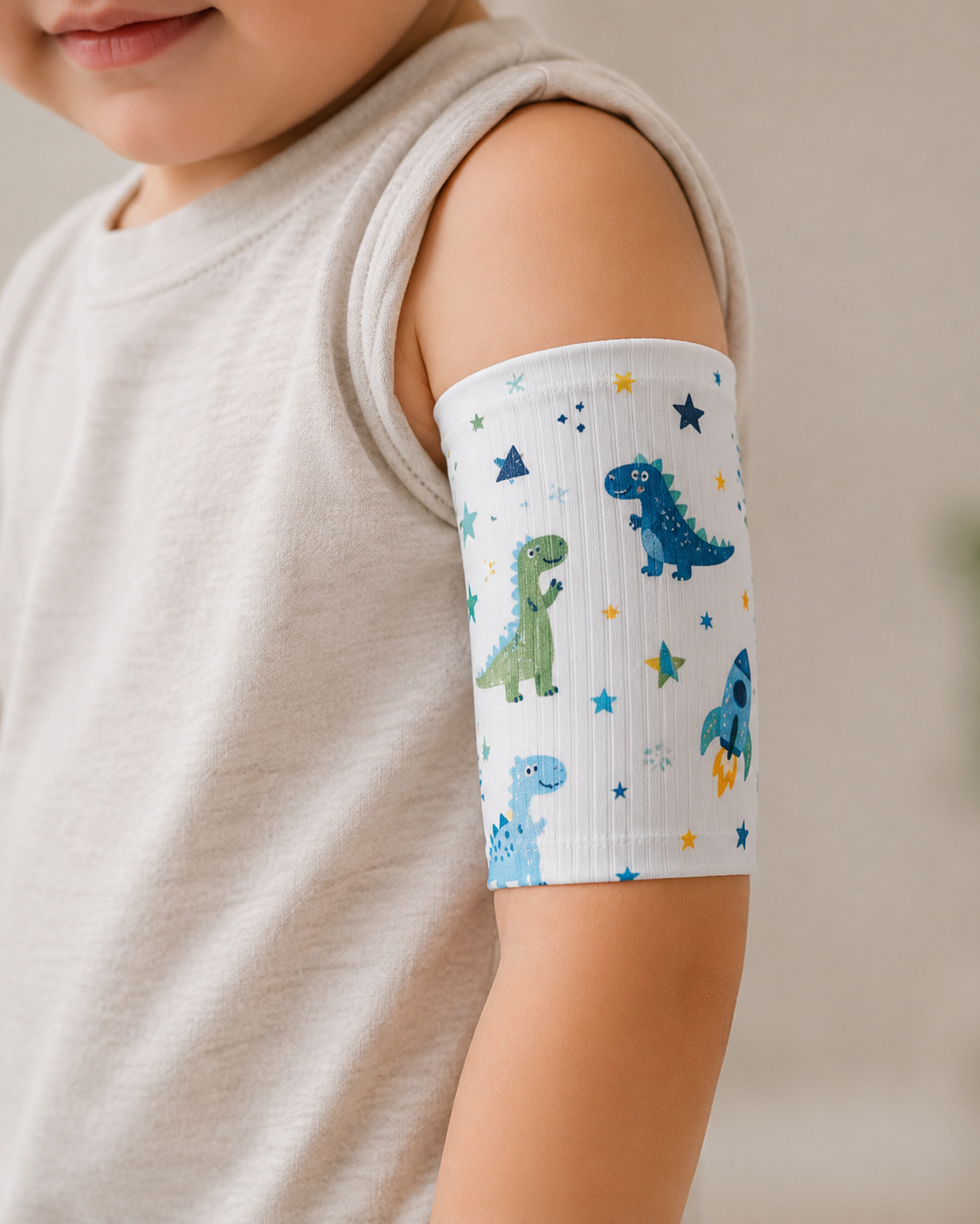 Child's arm with a dinosaur-patterned bandage on a neutral background